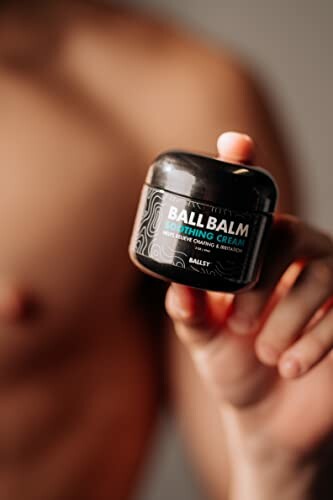 Hand holding Ball Balm soothing cream container