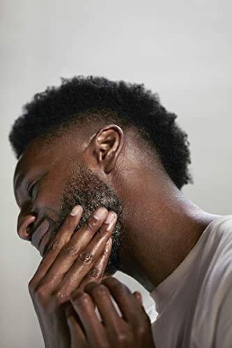 Side profile of a man touching his beard